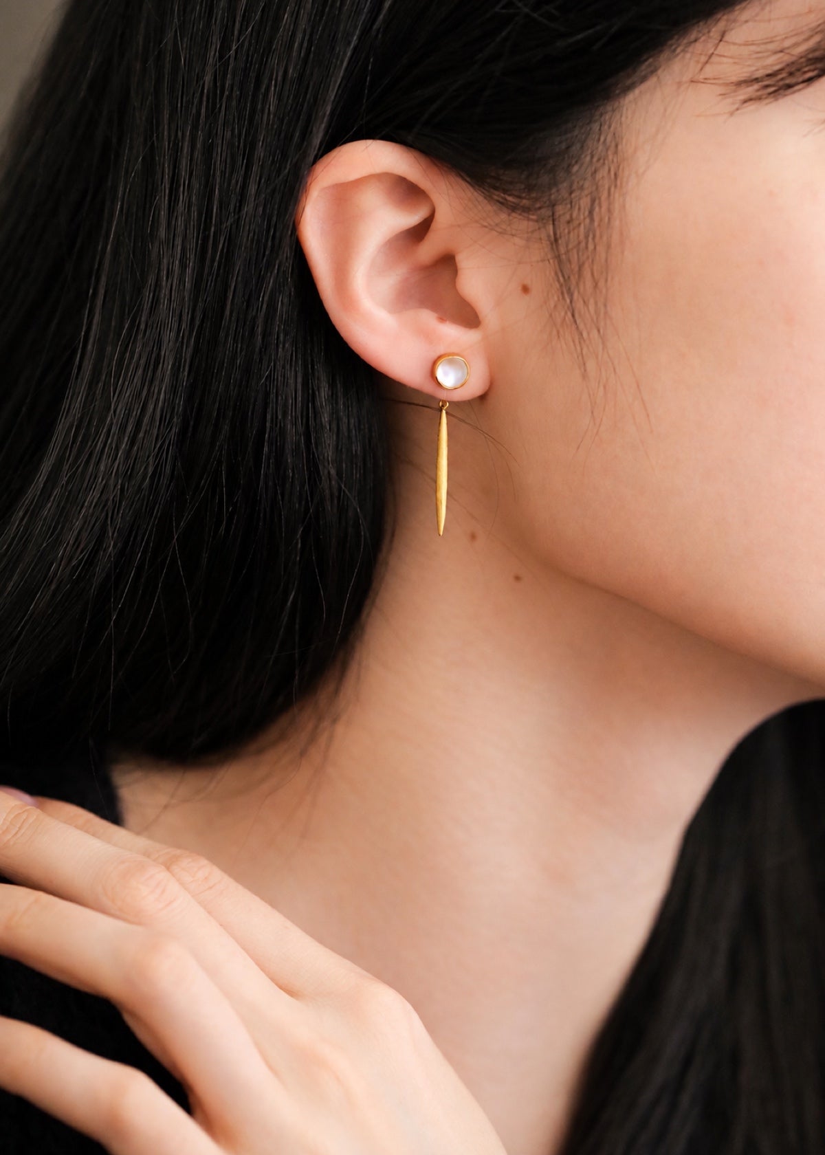 Moonstone bar dangle earring worn beside dark hair