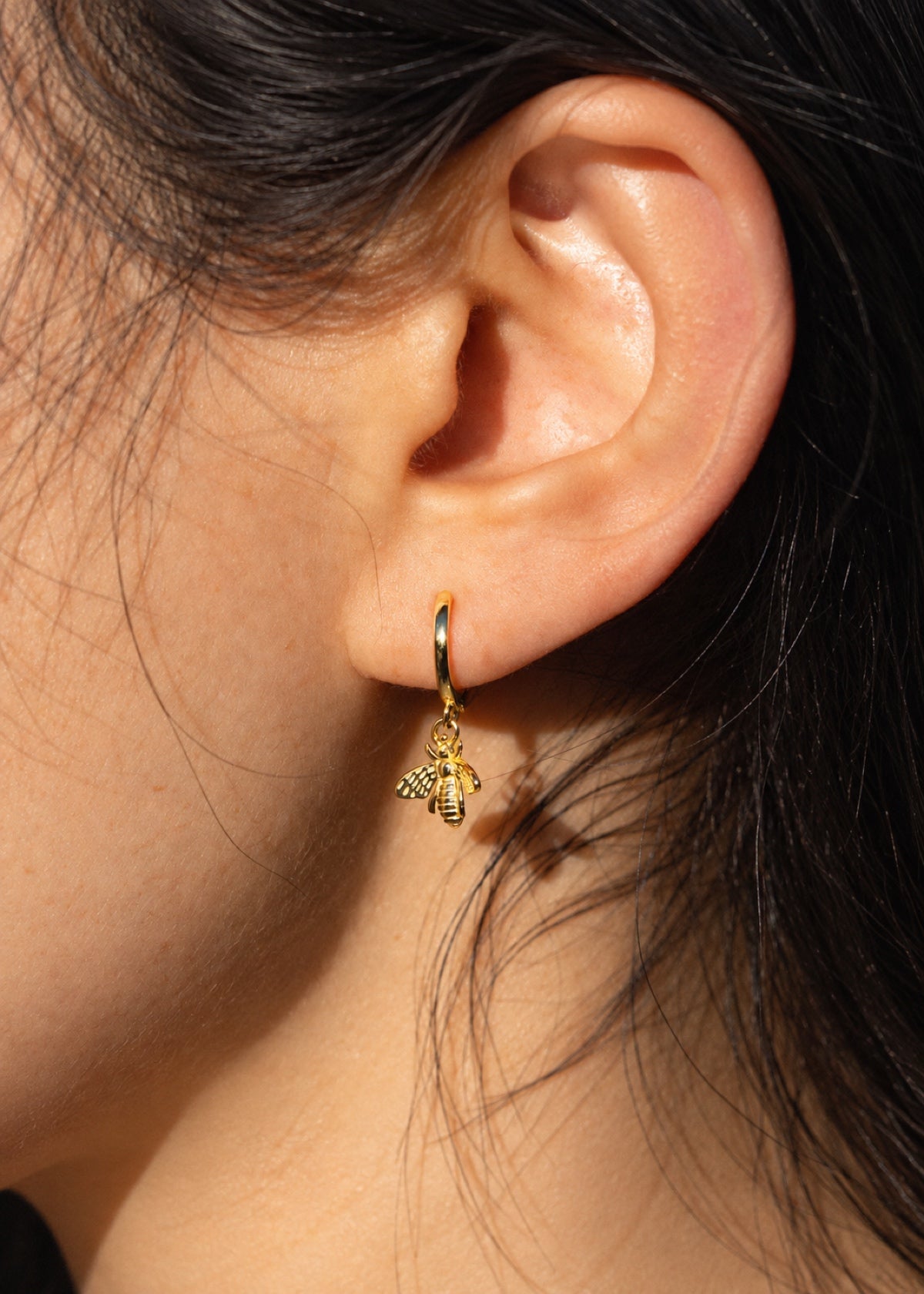 Close-up of a Bumblebee Huggie earring worn in an earlobe