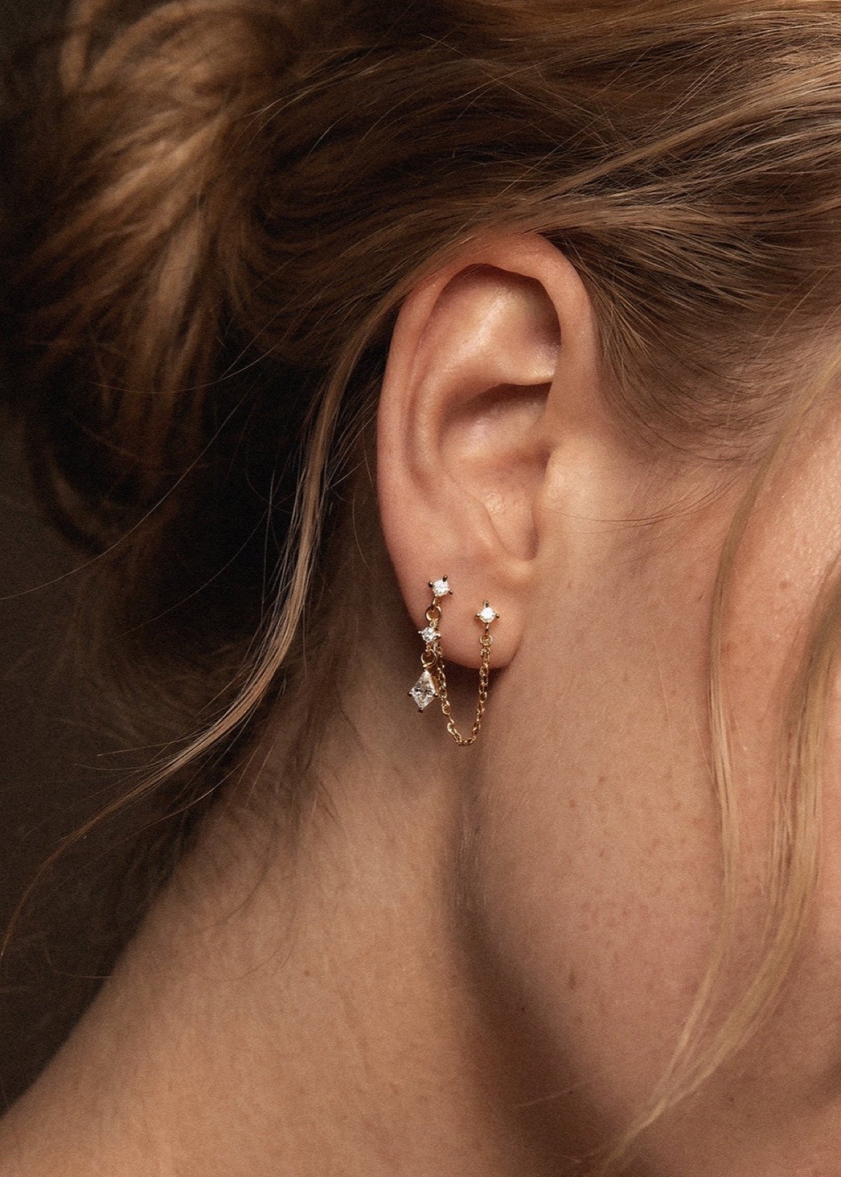 Double-piercing chain earring worn across two earlobe piercings