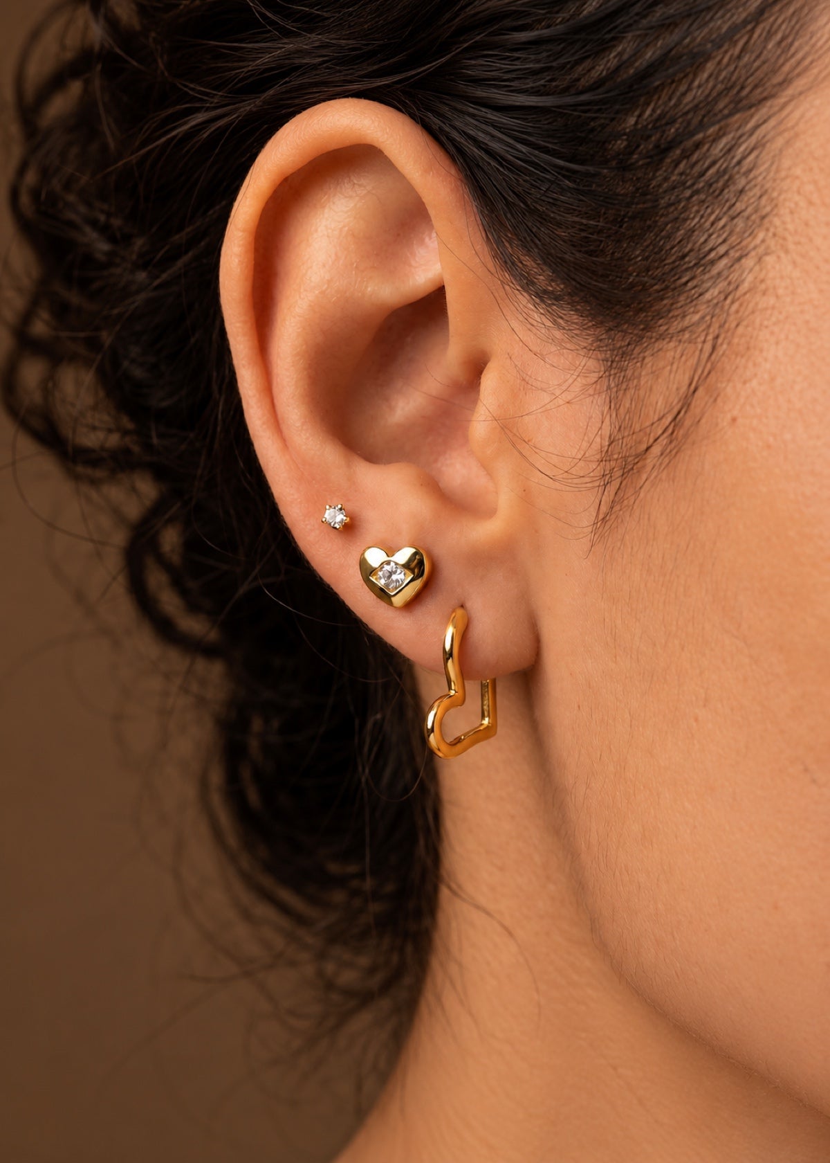 Close-up of a heart earring stack with CZ studs and a gold hoop