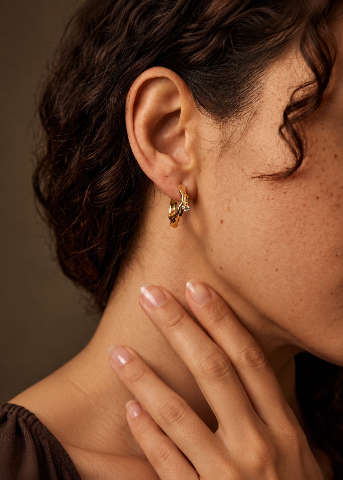 Wave Huggie earring worn with the wearer’s hand beside her face