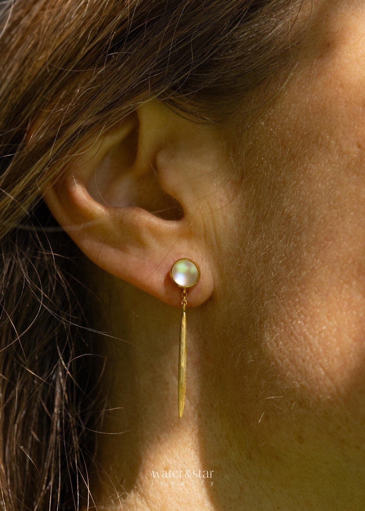 Close-up of a moonstone stud with a long gold bar drop