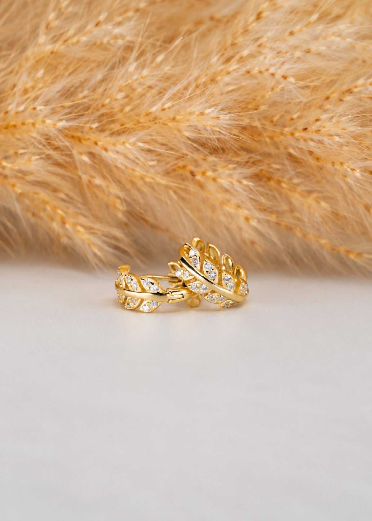 Olive Leaf huggies showing CZ details beside dried grasses