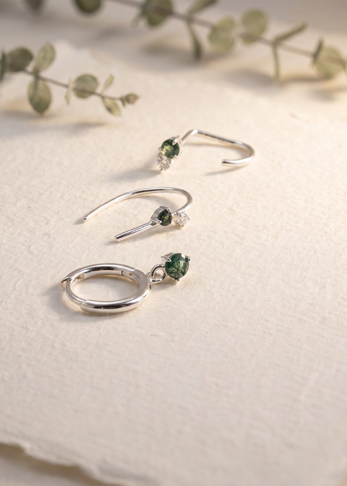 Silver Monet-inspired moss agate earrings arranged on a stone slab