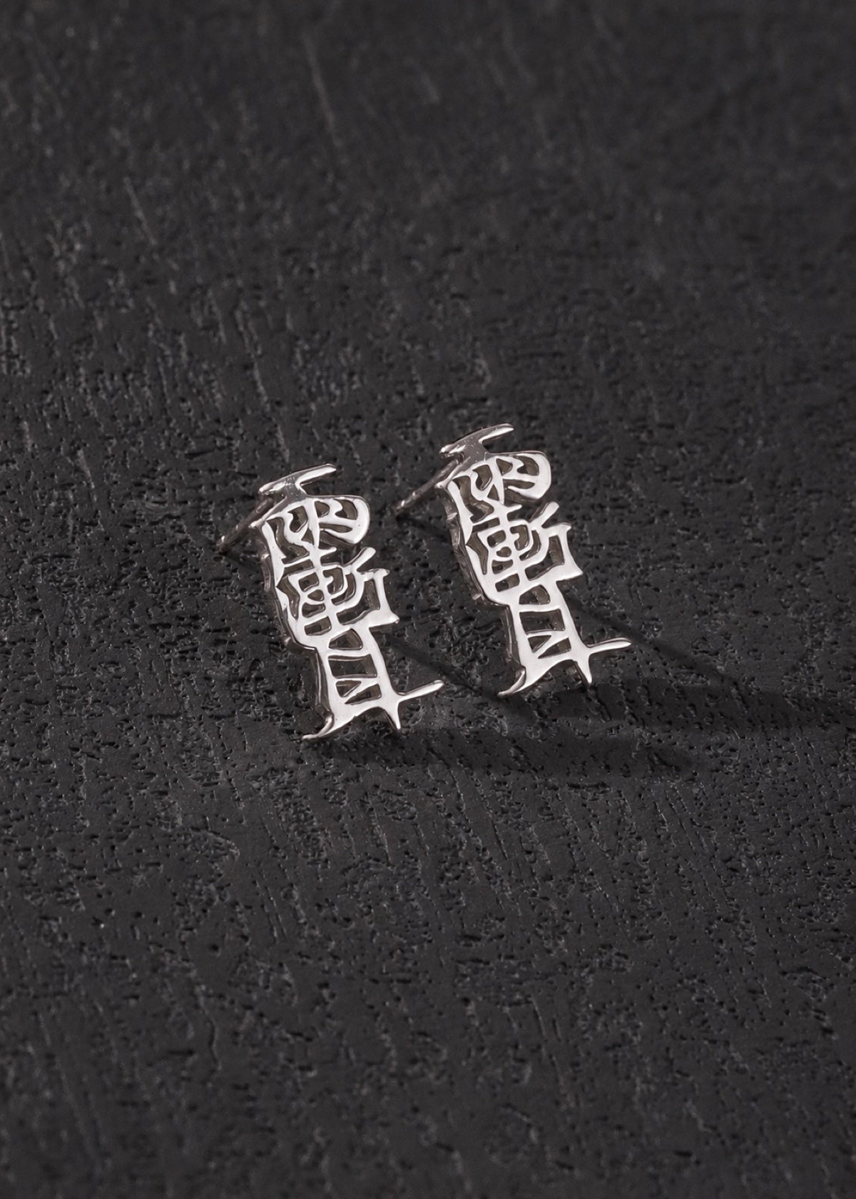 Taoist Amulet studs displayed against dark stone