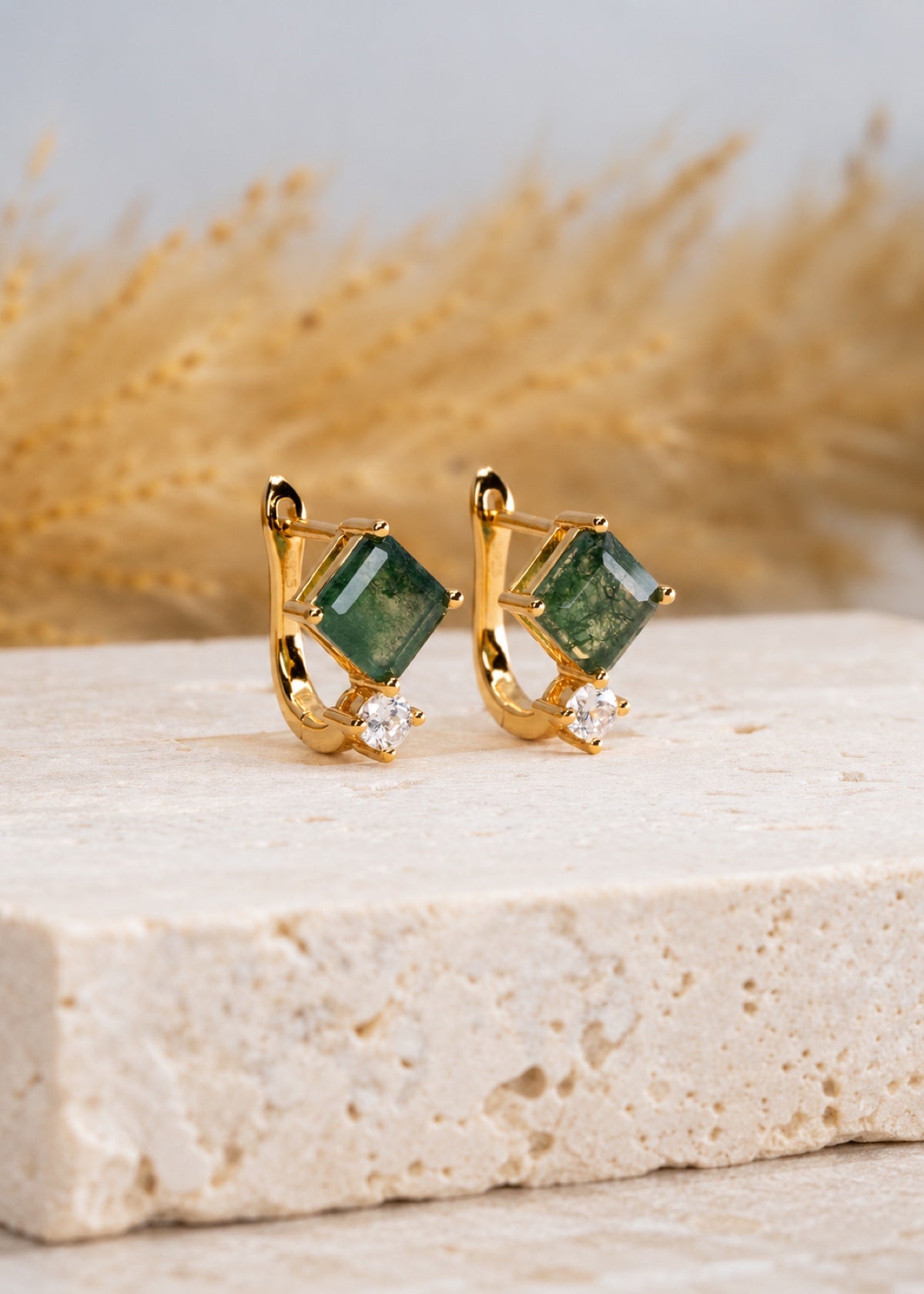 Gold square moss agate huggies standing on a stone block