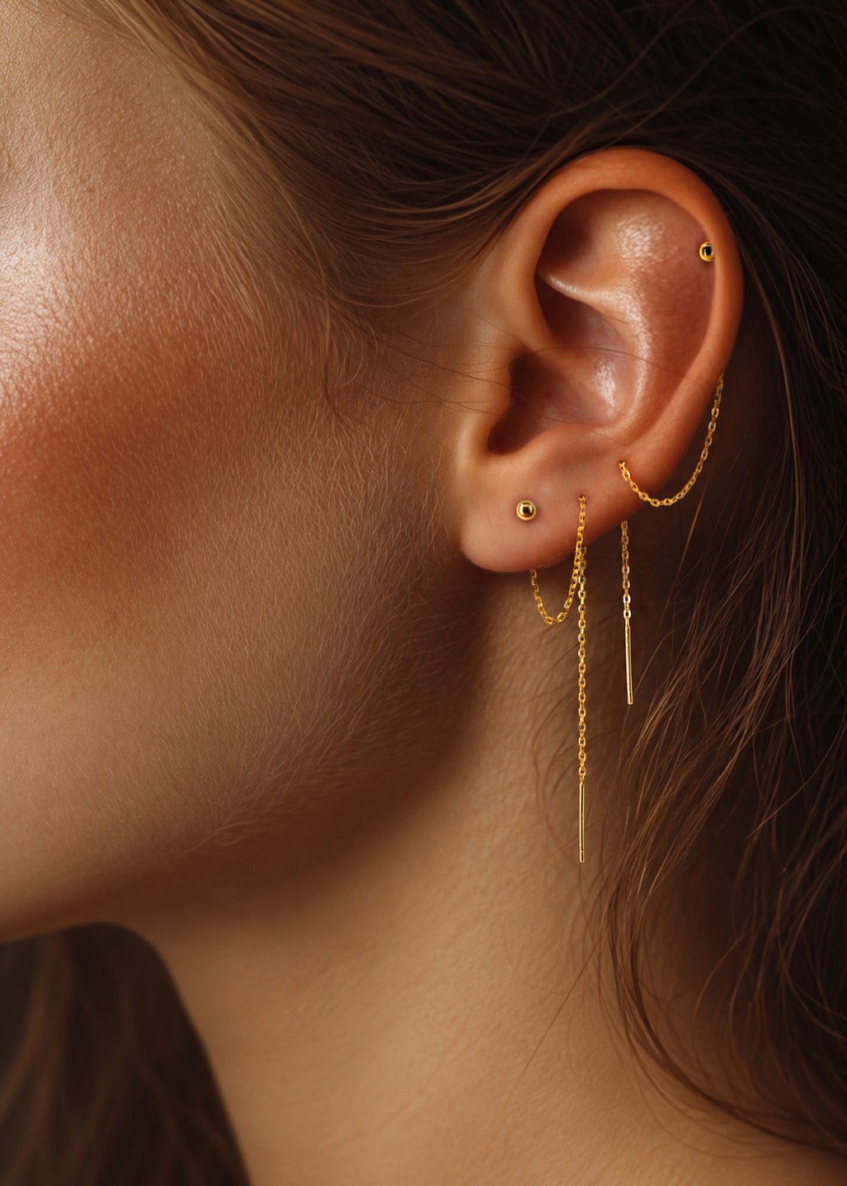 Ball threader chain looped through piercings with long ends hanging below the ear
