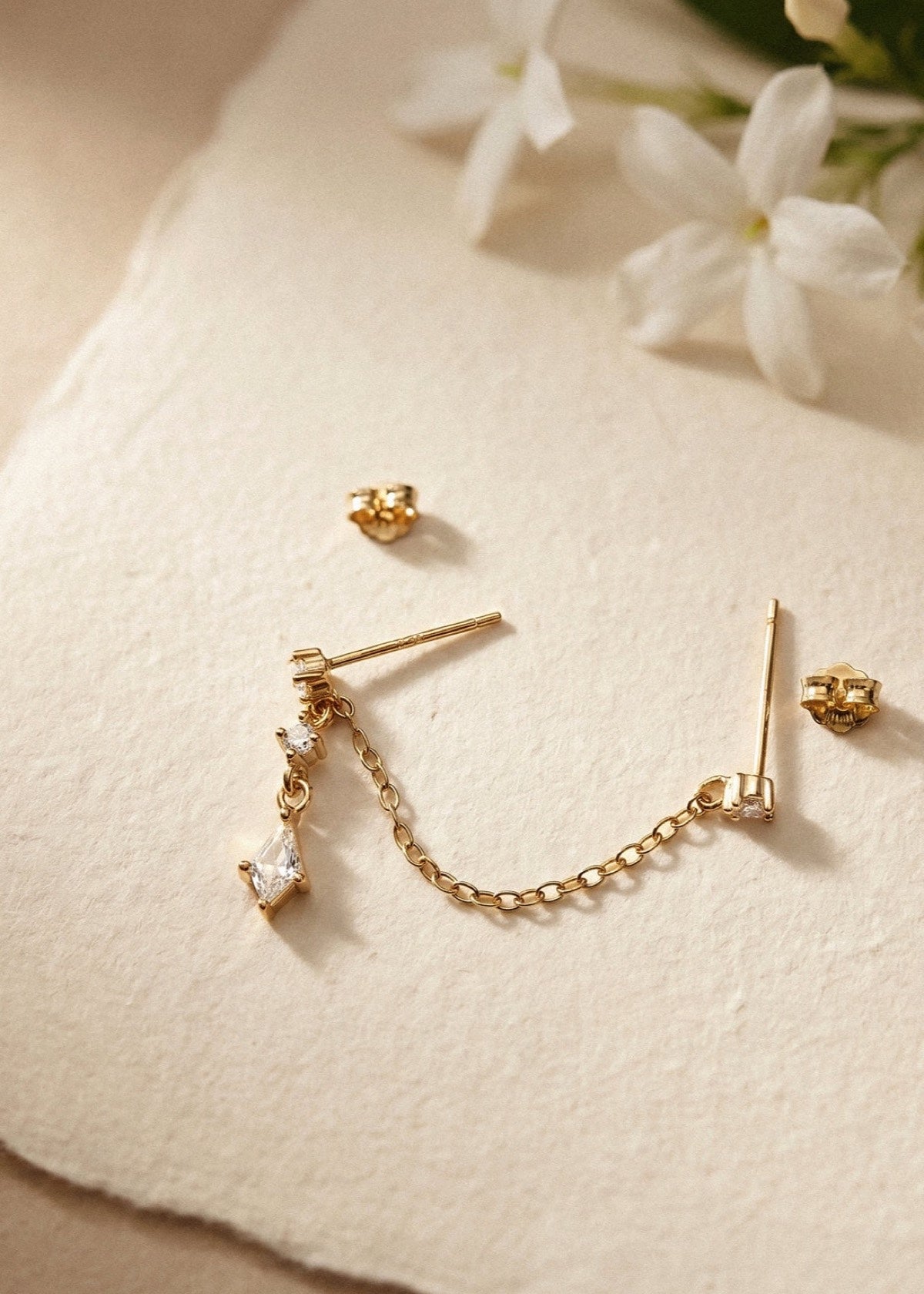 Double-piercing chain earring laid flat to show studs, posts and backs