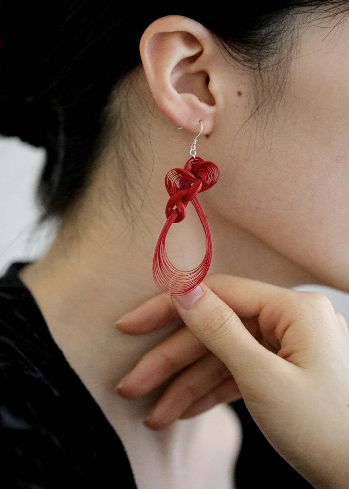 Red bamboo woven earring worn beside dark hair