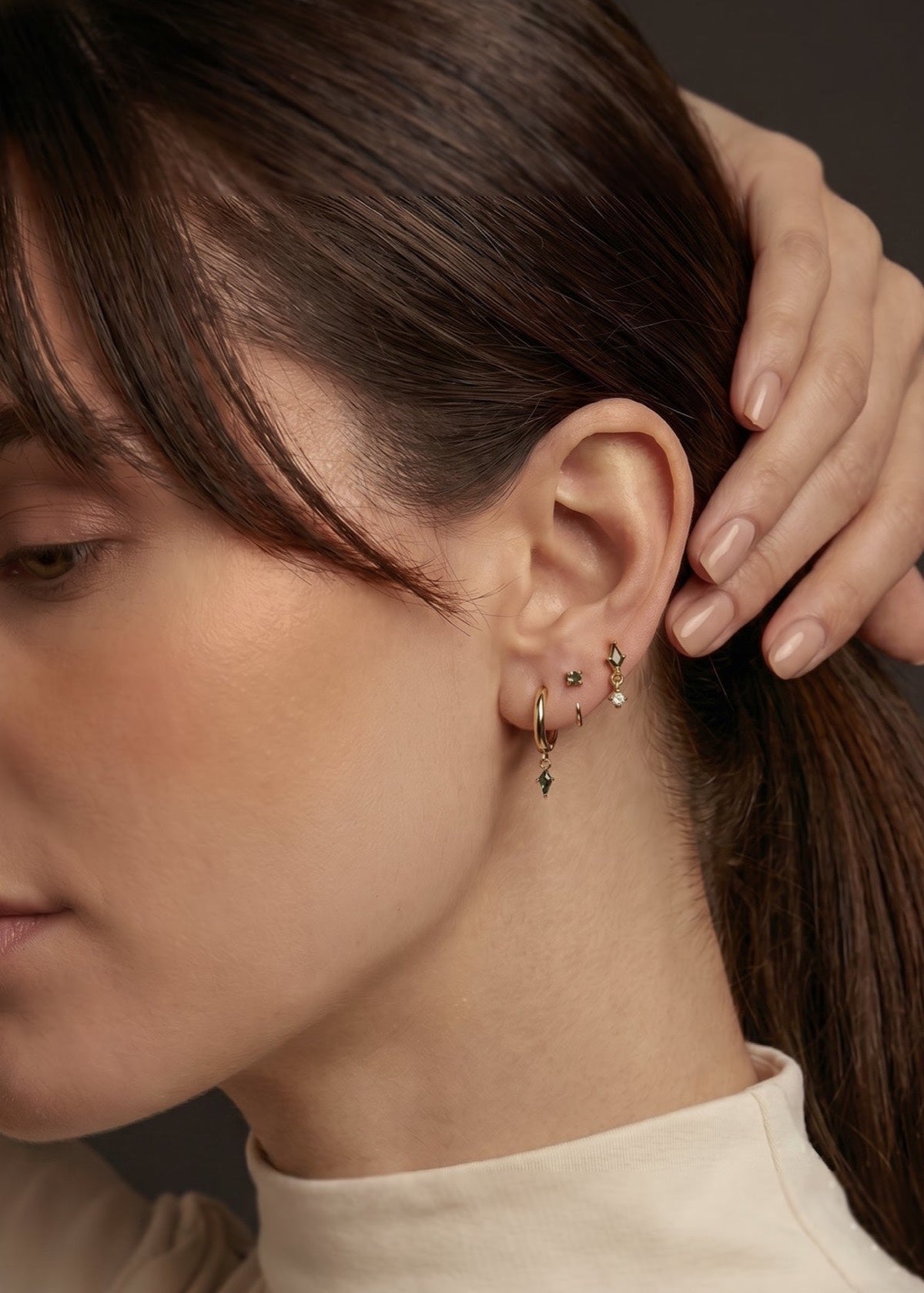 Moss agate earrings worn as a gold ear stack beside swept-back hair