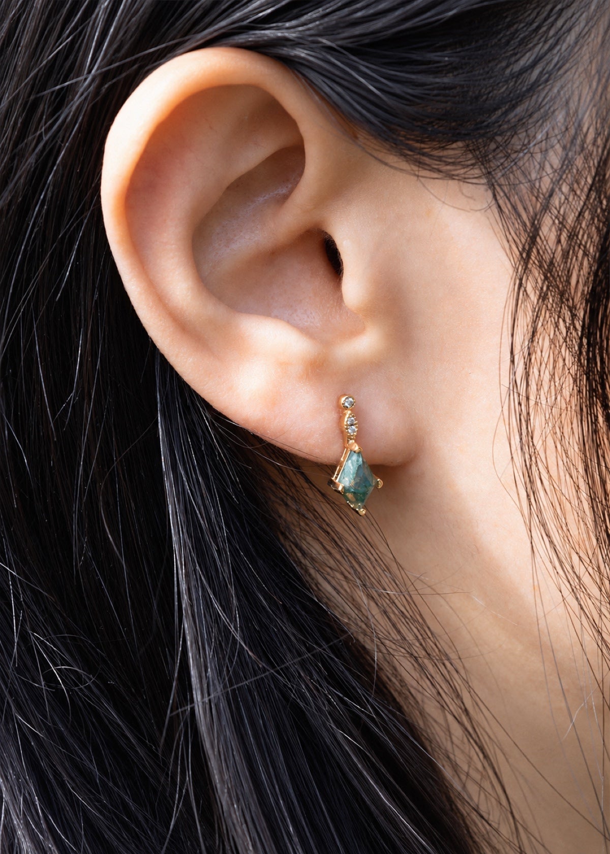 Moss agate hoop earring worn beside dark hair