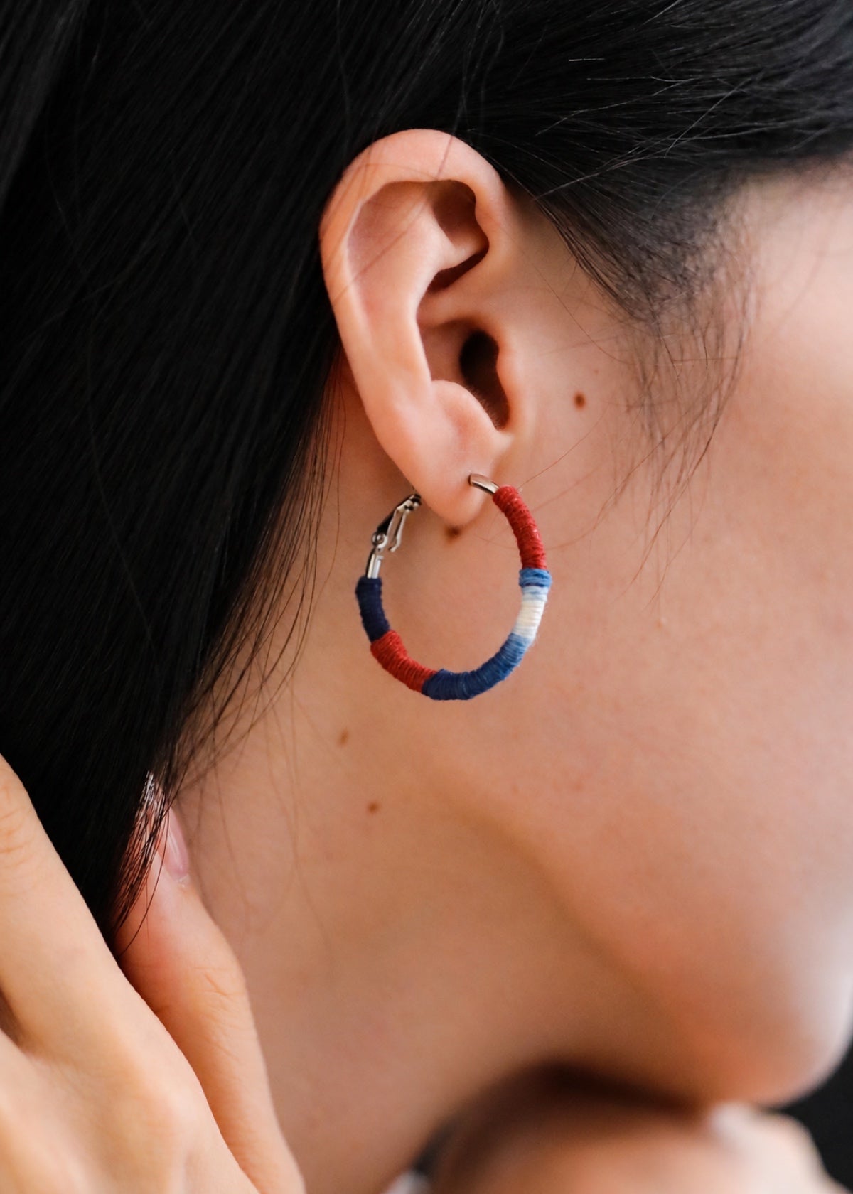 Close-up of a red, blue and white Shibori hoop worn in an earlobe