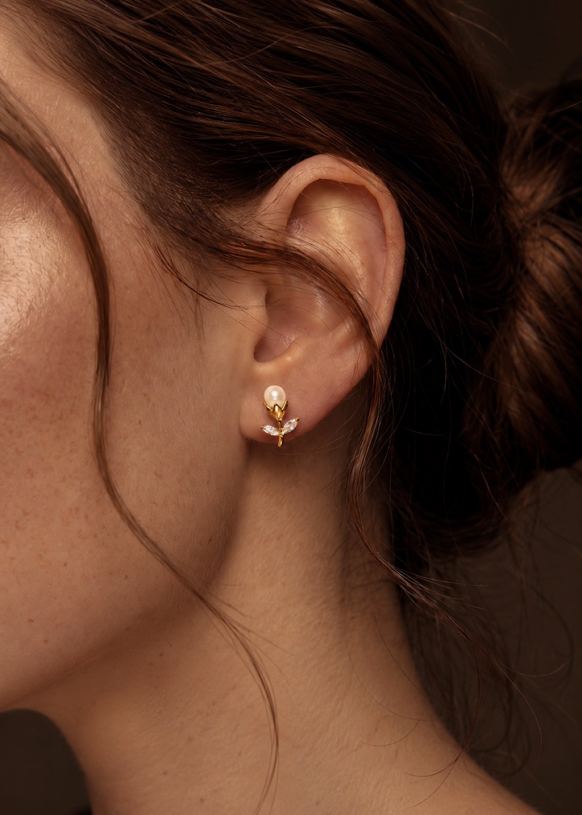 Close-up of a gold tulip stud showing pearl and leaf details