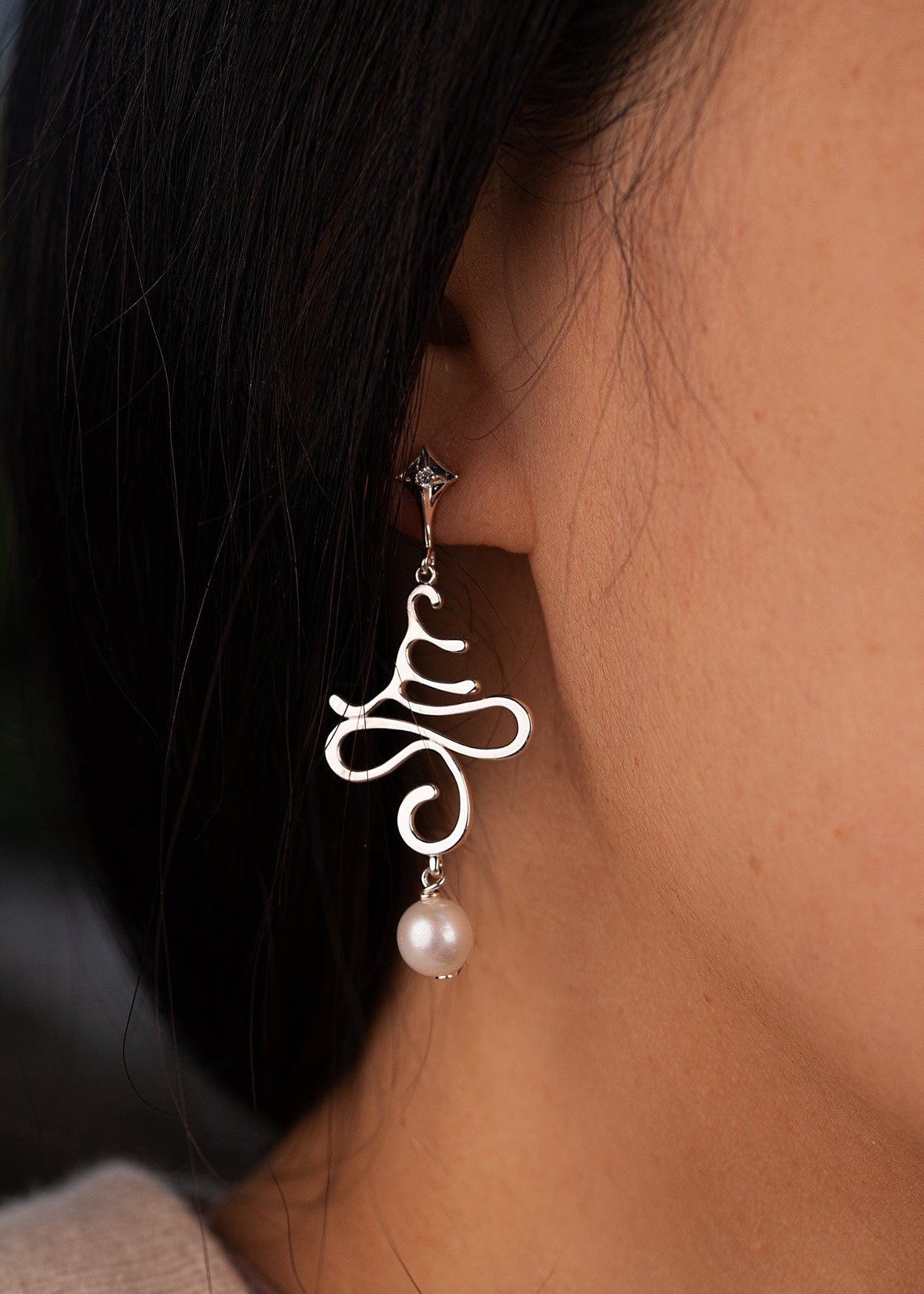 Silver OM Tree earring worn beside dark hair