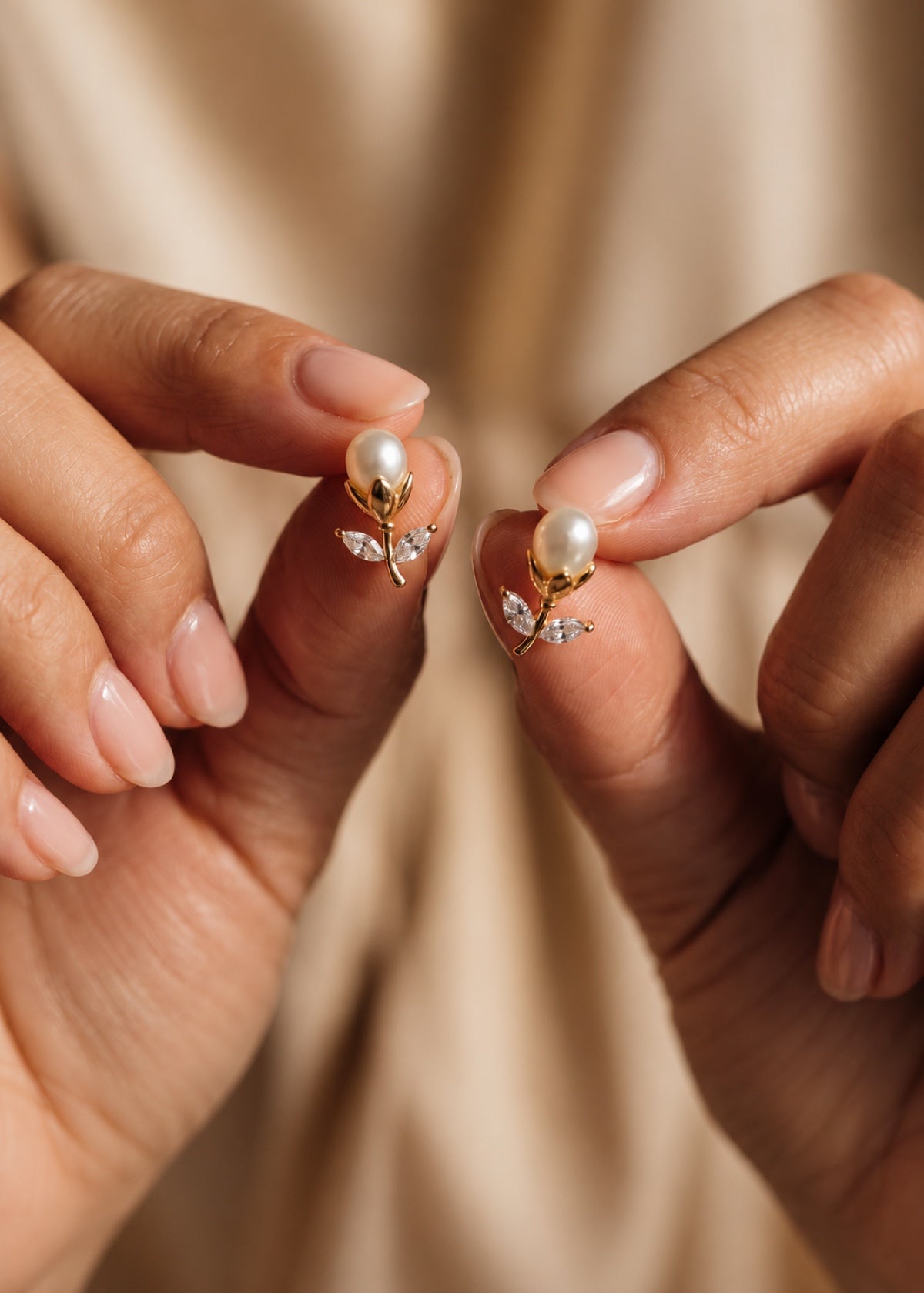 Hands holding tulip pearl studs to show their front details