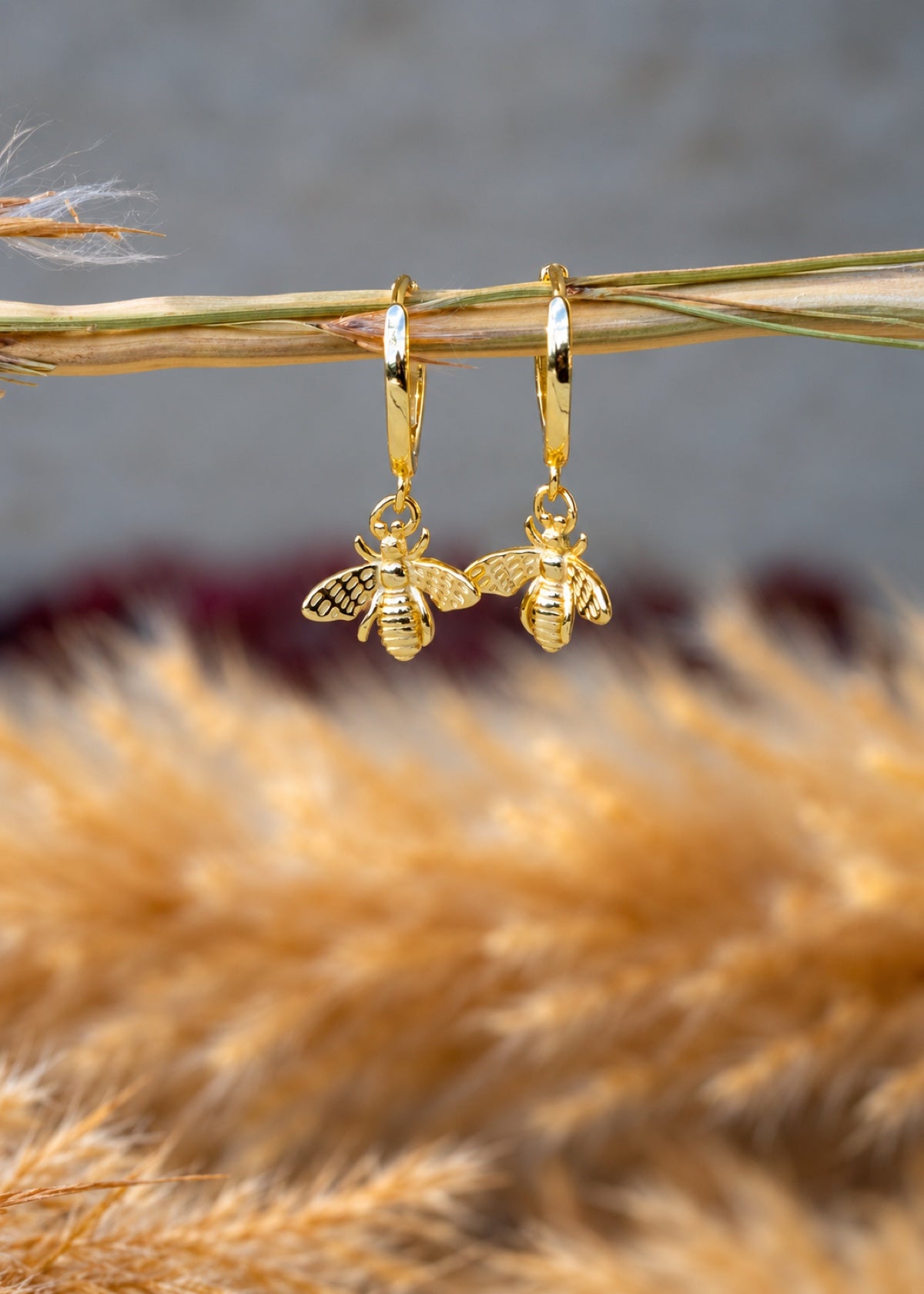 Gold Bumblebee Huggies hanging from a slender branch