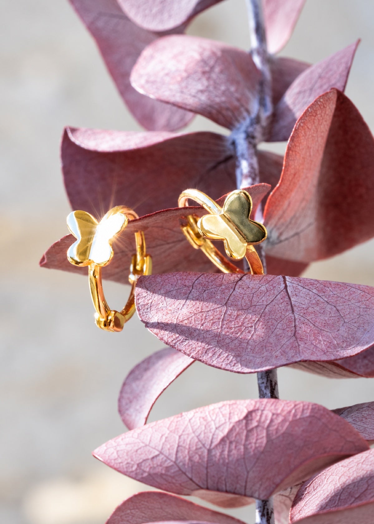 Gold Butterfly Huggies displayed on purple leaves