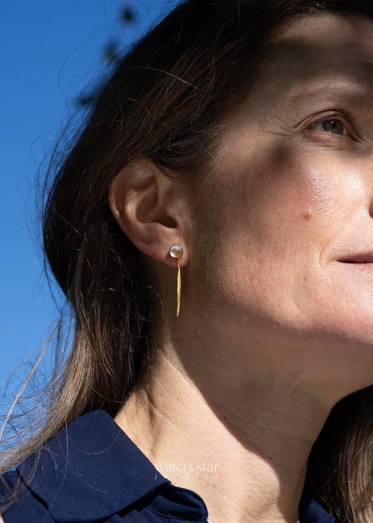 Bar dangle earring worn outdoors against a blue sky