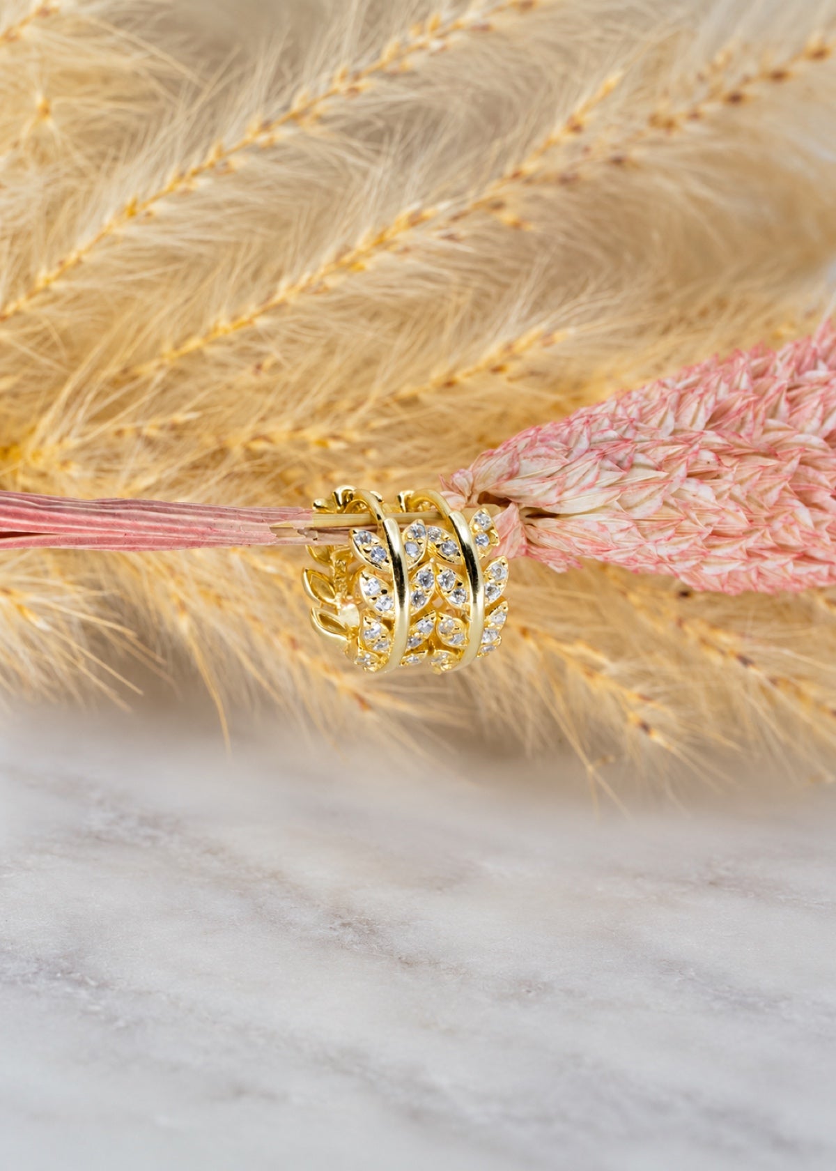 Olive Leaf huggies arranged beside golden and pink dried grasses