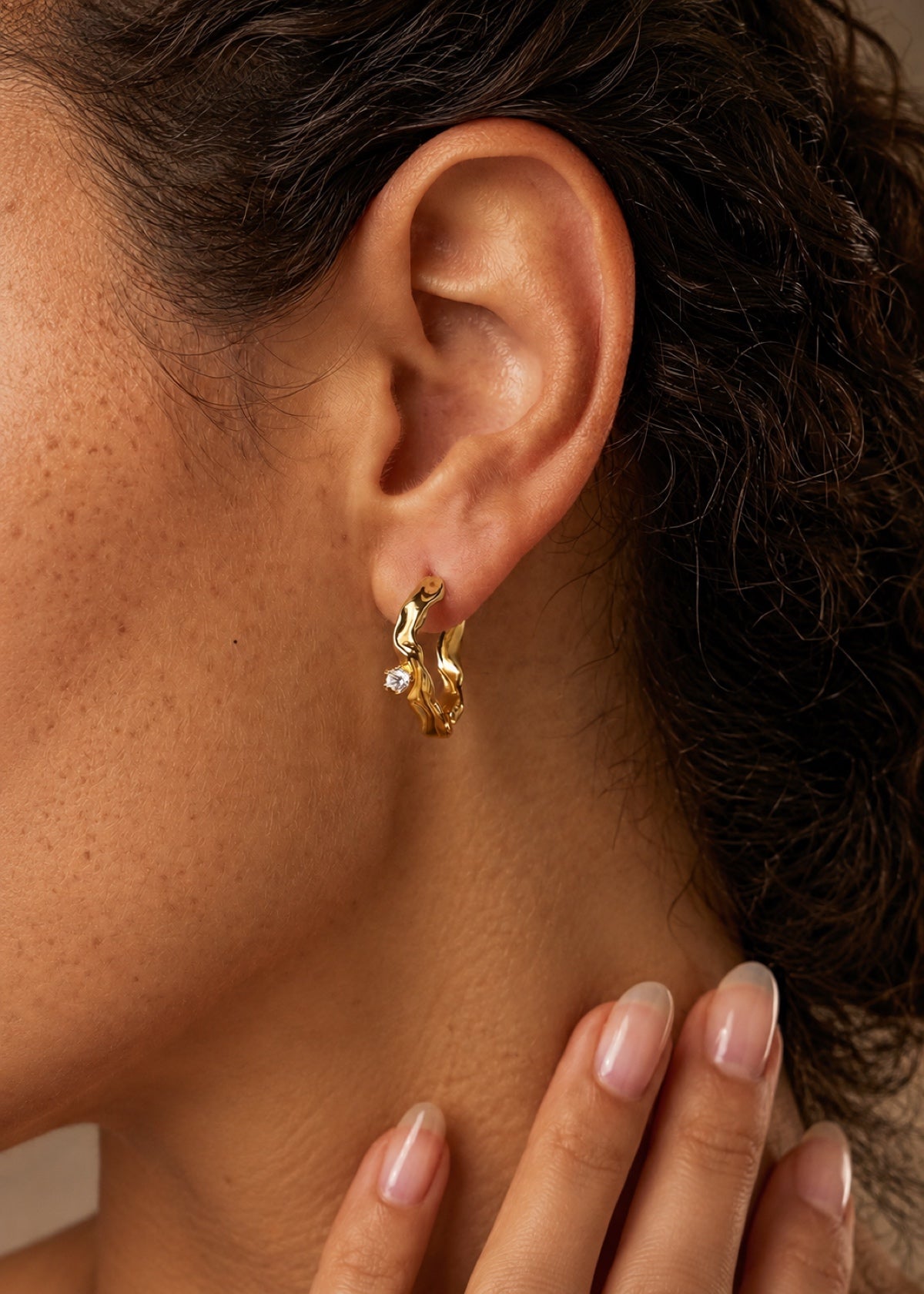 Close-up of a Wave Huggie earring worn in an earlobe