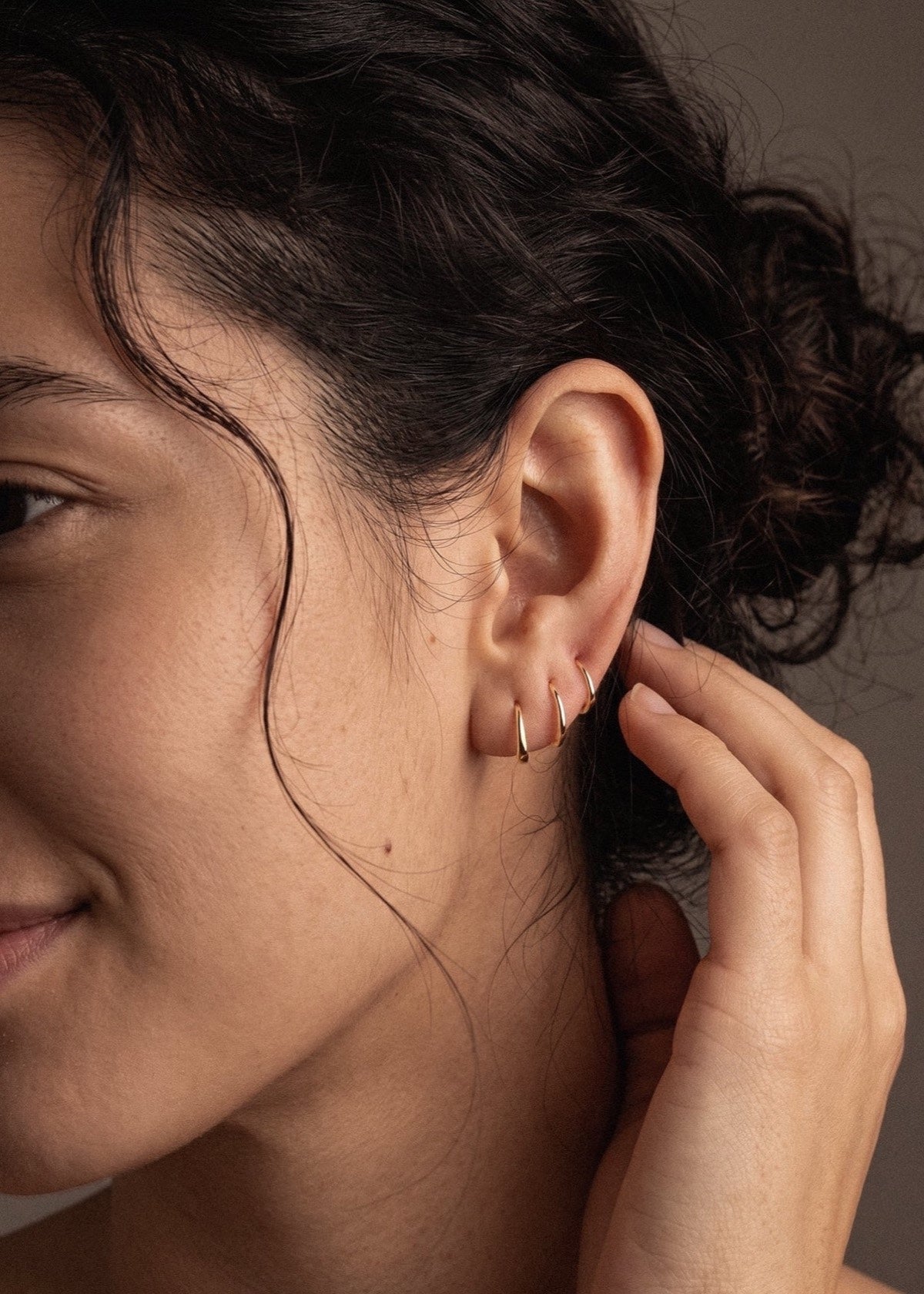 Gold D Shape sleeper earrings worn as a three-hoop ear stack