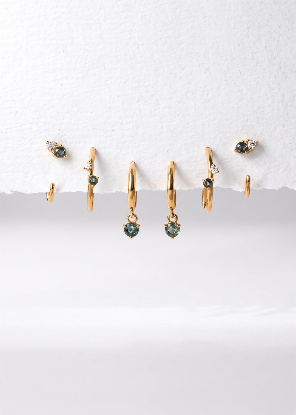 Gold Monet-inspired moss agate huggies and studs arranged as a collection